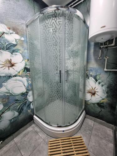 a shower in a bathroom with flowers on the wall at Apartman Melody in Paraćin