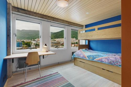 a bedroom with a bed and a desk and windows at Unique gem overlooking the world famous Bryggen in Bergen