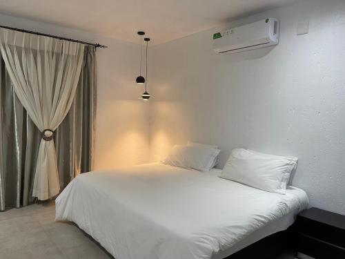 a white bed in a room with a window at Massala Beach Resort, Lda in Vila Praia Do Bilene