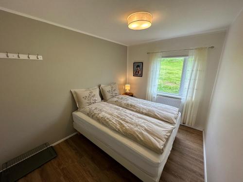 Habitación pequeña con cama y ventana en Litla-Sandfell Guesthouse, en Stóra-Sandfell