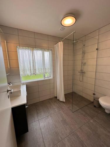 La salle de bains est pourvue d'une douche, de toilettes et d'une fenêtre. dans l'établissement Litla-Sandfell Guesthouse, à Stóra-Sandfell