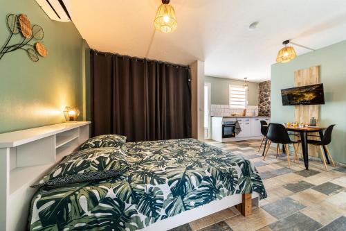 Un dormitorio con una cama y una cocina con una mesa. en Le Grand Colibri, en Saint-Denis
