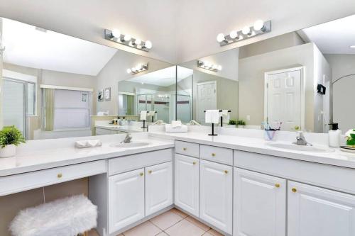 a white bathroom with two sinks and two mirrors at Lakeview Luxury Oasis in Kissimmee