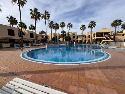 a large swimming pool in a courtyard with palm trees at Alquilaencanarias Tagoro Paradise in Costa Del Silencio