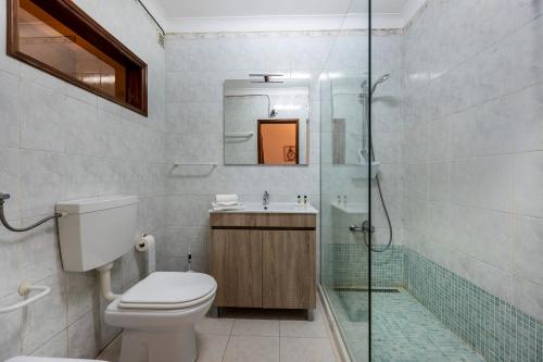 y baño con aseo, lavabo y ducha. en Casa Avenida en Lagos
