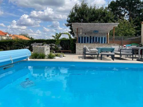 a blue swimming pool with chairs and a table at Charmant T1 privé avec vue et accès piscine in Basse-Goulaine