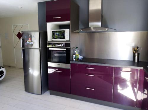 a kitchen with purple cabinets and a stainless steel refrigerator at Charmant T1 privé avec vue et accès piscine in Basse-Goulaine