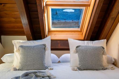 a bed with two pillows and a window at Valle de Sueños in Escarrilla