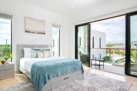 a white bedroom with a bed and a large window at Private Pool Villa, Long Bay Beach with VIP Extras in Long Bay Hills
