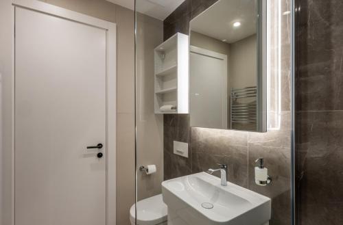 een badkamer met een wastafel, een toilet en een spiegel bij Belgrade Center Apartment Lux 1 in Belgrado