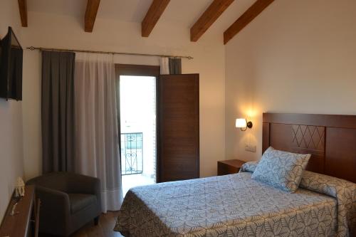 a bedroom with a bed and a chair and a window at Casa Rural La Madroña in Fuentelabrada de los Montes