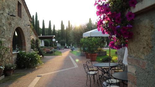 a patio with tables and chairs and purple flowers at Agriturismo La Sovana in Sarteano