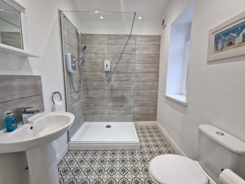 y baño con ducha, aseo y lavamanos. en 5 Bedroom modern home with parking. Near Brecon Beacons & Bike Park Wales, en Merthyr Tydfil