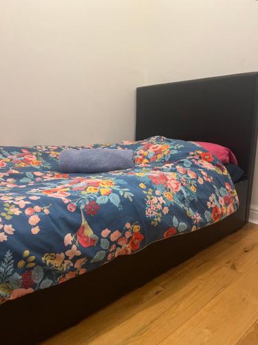 ein Bett mit blauer Bettdecke und Blumen drauf in der Unterkunft Ilford Tiny Jewel in Ilford