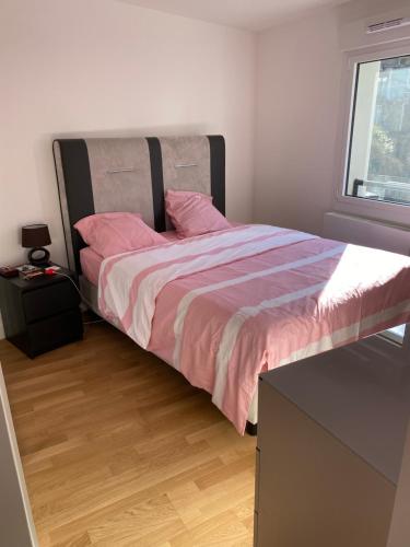 een slaapkamer met een bed met roze lakens en een raam bij Villa du Centre in Annemasse