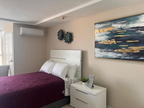 een slaapkamer met een bed en een schilderij aan de muur bij Sun Flower in Portmore