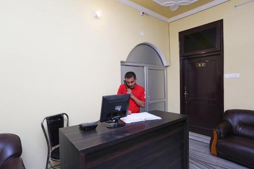 a man talking on a phone at a desk with a computer at Flagship Greenview Near Munshi Pulia Metro Station in Vibhuti Khand