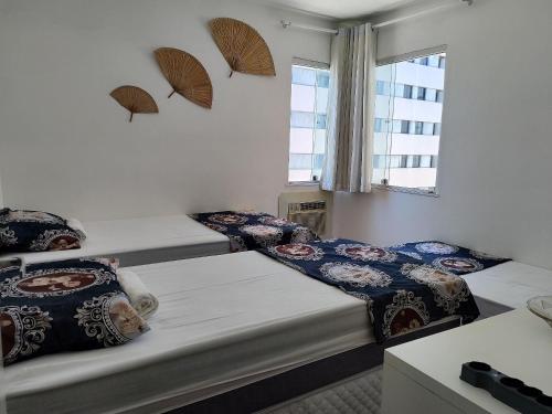 a room with three beds and a window at Seaside Season Maceió in Maceió