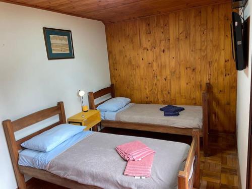 2 camas en una habitación con paredes de madera en Casa Aconchegante em Monte Verde en Camanducaia