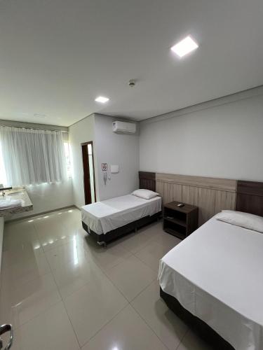 a hotel room with two beds and a mirror at Hotel PetroShop in Palmas