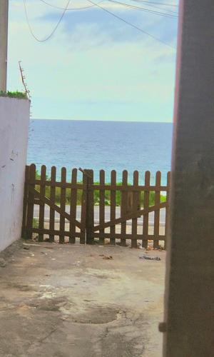 einen Holzzaun mit dem Ozean im Hintergrund in der Unterkunft Casa simples de frente para praia 5km do centro in Saquarema