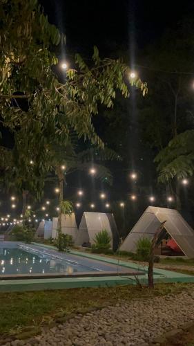 una piscina del complejo por la noche con tiendas de campaña en Villa Kolah Watu en Wonosobo