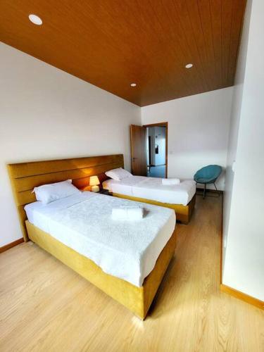 a hotel room with two beds and a chair at A Casa da Concha in Rabo de Peixe