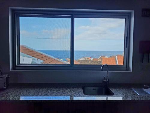 a kitchen window with a view of the ocean at A Casa da Concha in Rabo de Peixe