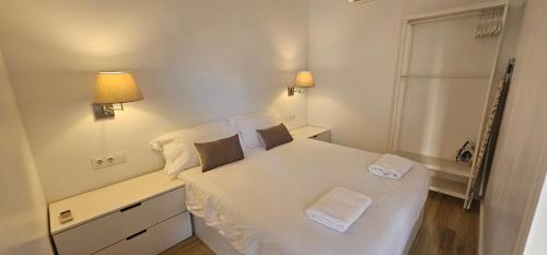 ein kleines Schlafzimmer mit einem weißen Bett mit zwei Kissen in der Unterkunft Apartamento Playa Mar in Castelldefels