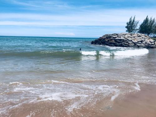 a person in the water near a rock in the ocean at Casa na praia do centro in Marataizes