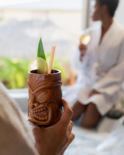 a person holding a cup with a plant in it at Hôtel Iloma in Sainte-Luce