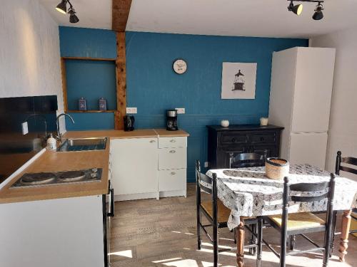 a kitchen with a table and a sink and a table and a refrigerator at Gîte du moulin Mont Saint Michel in Pontorson
