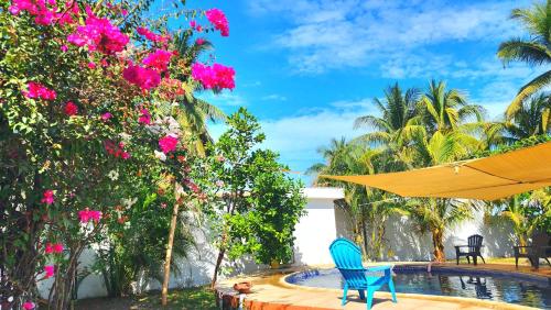 une terrasse avec une chaise bleue, un parasol et des fleurs dans l'établissement Casa Guadalupe, à Sipacate
