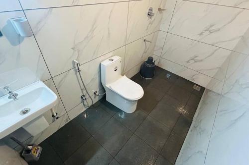 a bathroom with a white toilet and a sink at Aadhya Homestay 4BHK in Wayanad