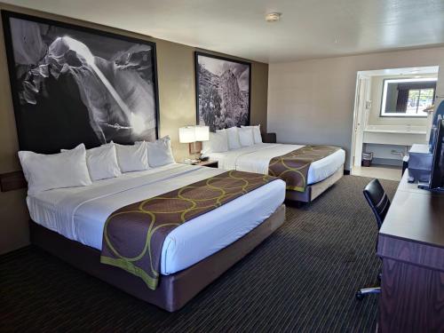 a hotel room with two beds and a desk at Super 8 by Wyndham Wickenburg AZ in Wickenburg