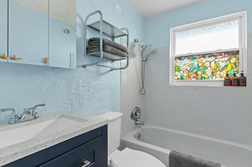 a bathroom with a sink and a tub and a window at Downtown Punta Gorda 3 bd Bungalow in Punta Gorda