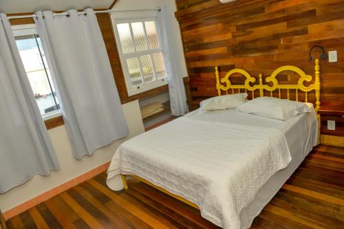a bedroom with a white bed with two windows at Verde Vida Ecopousada - Termas do Gravatal in Gravatal