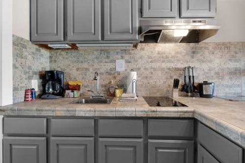 a kitchen with gray cabinets and a sink at The Tides by the Sea in Seaside