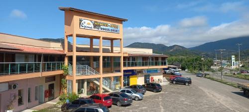 ein großes Gebäude mit Autos auf einem Parkplatz in der Unterkunft Kitnetes & Aptos Praia do Capricórnio in Caraguatatuba
