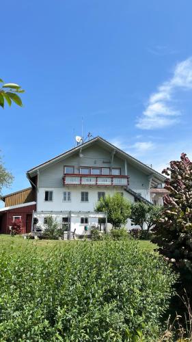 a large white building with red trim on a field at Allgäuhaus Thomas am Bauernhof Ferienwohnung in Wald