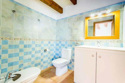 Un baño con azulejos azules, inodoro y lavabo. en Villa Anita, en Santo Tomás