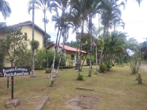 un panneau devant une maison plantée de palmiers dans l'établissement Pousada Porto Aventura -Chalés da Luci, à Peruíbe