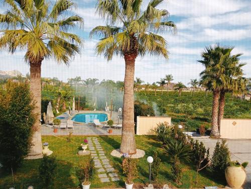 a garden with palm trees and a swimming pool at Villa Laura Apartment in Giardini Naxos