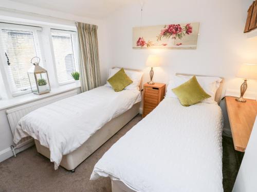 dwa łóżka w pokoju z dwoma oknami w obiekcie Fleece Cottage w mieście Holmfirth