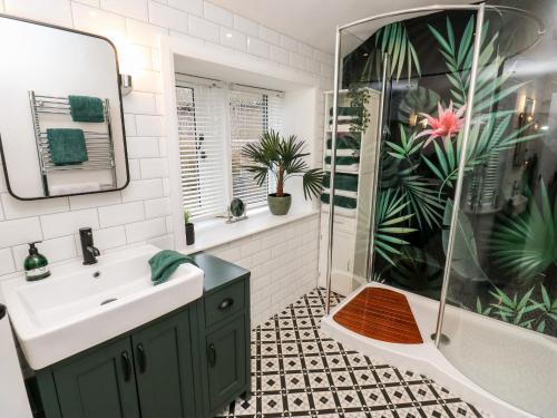 ein Badezimmer mit einem grünen Waschbecken und einer Dusche in der Unterkunft Fleece Cottage in Holmfirth