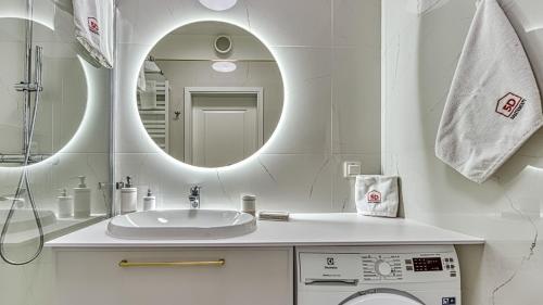 a white bathroom with a sink and a mirror at Rezydencja Niechorze 314 z Widokiem na Morze - 5D Apartamenty in Niechorze