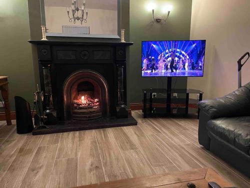 a living room with a fireplace and a flat screen tv at Ballinderry Station Cottage - Beautiful Holiday Cottage in Ballinderry Upper