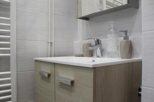 een witte badkamer met een wastafel en een spiegel bij Logement calme + stationnement in Troyes