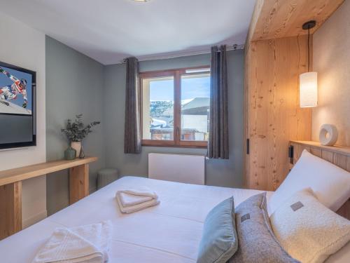 Un dormitorio con una cama blanca y un televisor. en Charmant appartement 3 pièces proche des pistes avec balcon, cuisine équipée et garage à l'Alpe d'Huez. - FR-1-645-52, en LʼHuez