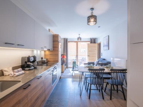 une cuisine avec une table et des chaises dans une pièce dans l'établissement Appartement Luxueux avec Terrasse et Parking Ergonomique près des Pistes, Vieil Alpe - FR-1-645-65, à Huez